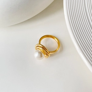 Bague fleur en acier titane avec perle centrale sur un fond blanc très minimaliste
