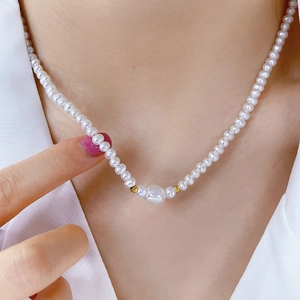 Close-up of small pearl necklace featuring a large baroque pearl and gold bead details