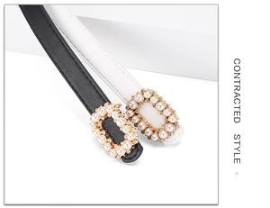 Detail of slim black and white leather belts with pearl and rhinestone gold buckles
