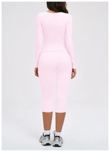 Rear view of pink athletic set featuring tight long sleeve top and capri yoga leggings