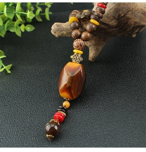 Detailed view of ethnic style long necklace with agate stone, wooden beads and metal knot