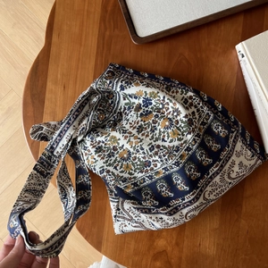 Détail d'un sac cabas en coton bohème posé à plat sur une table en bois de style rétro
