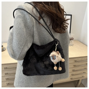 Detail of black plush tote bag with a cute sheep charm on a thin shoulder strap