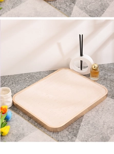 Detail of beige jewelry tray with brushed gold metal frame on a textured modern surface