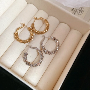 Macro detail of gold and silver irregular textured hoop earrings in velvet jewelry box