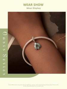 Détail macro du pendentif scarabée avec pierres vertes sur bracelet en maille argentée