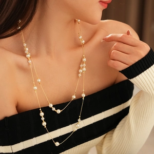Detail of a double-layered gold chain necklace with interspersed white faux pearls