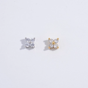Macro detail of silver and gold clover pendants with clear zircons on gray background