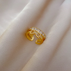 Close-up of golden bow-knot ring with micro-pave zircons on a soft silk background