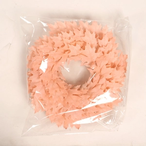 Pink artificial Christmas wreath with faux maple leaves in protective packaging