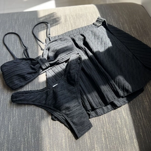 Detailed view of black three-piece bikini set featuring textured eyelet mesh fabric