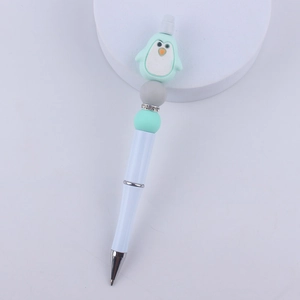 Detail of beaded ballpoint pen featuring a mint green cartoon penguin and rhinestone charms