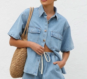 Detail of light blue denim shirt set showing collar, buttons and front pocket texture