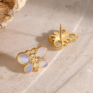 Detail view of golden butterfly stud earrings with purple opal wings on stone base