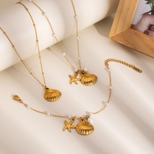 Close-up of golden shell and starfish charms with pearls on delicate chain jewelry set