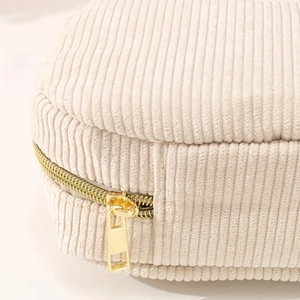 Macro view of beige corduroy cosmetic bag featuring a premium gold metal zipper detail