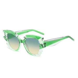 Green cat-eye sunglasses with faceted frames and gradient lenses on white background
