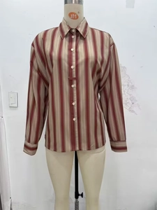 Détail de rayures verticales marron rouge et fermeture boutonnée sur chemise femme