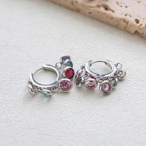 Silver hoop earrings with colorful round zircon pendants on natural stone background