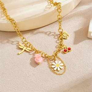 Golden necklace with cherry, daisy, and butterfly charms on a textured background