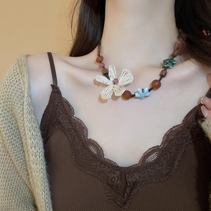 Detail of bohemian necklace with woven flower pendant and ceramic star beads on model