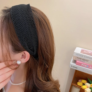 Detailed view of the black braided texture headband worn by a model with elegant pearls