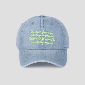 Détail de la casquette en denim bleu clair avec broderie de texte jaune fluo inspirant