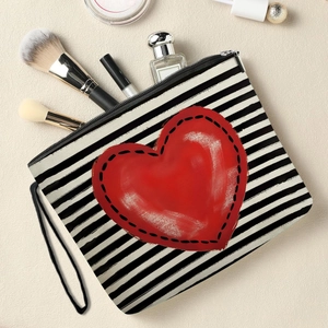 Striped cosmetic bag with red heart pattern showing makeup brushes and perfume inside