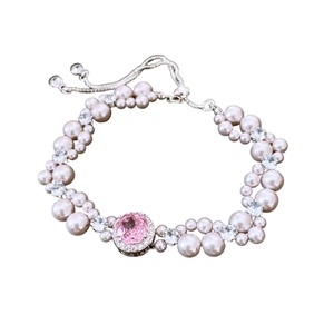 Elegant bracelet with pink pearls, sparkling crystals, and central pink stone on white background