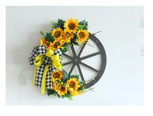 Detail of wooden wheel wreath with sunflowers and black-white checkered bow on white wall