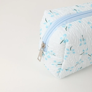 Detail of blue floral quilted fabric pencil case featuring a smooth zipper and metal pull