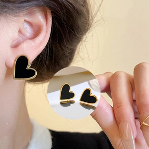 Minimalist black heart earrings with gold trim worn by a model in a warm setting