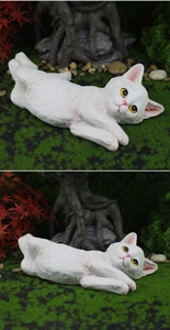 Macro detail of a white resin cat figurine featuring realistic fur texture and a side pose