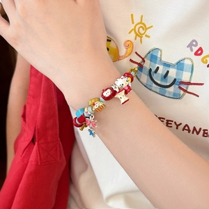 Gros plan détaillé d'un bracelet de perles avec breloques Hello Kitty et pomme au poignet