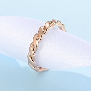 Macro shot of rose gold twisted rope ring on a white silk ribbon with blue background