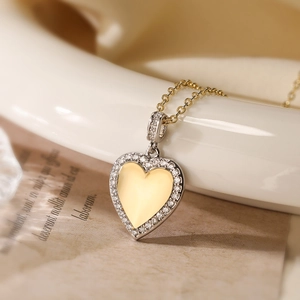 Two-tone gold plated heart pendant necklace with shimmering zircon crystals on white stand