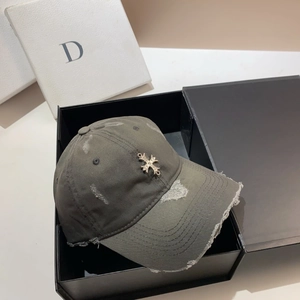 Detailed close-up of distressed army green cotton baseball cap with metal cross in a gift box