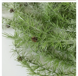 Close-up of artificial pine needles with snow flocking and natural pine cones