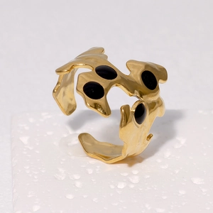 Detail eines 18k vergoldeten Edelstahlrings mit flüssiger Form und schwarzen Punkten