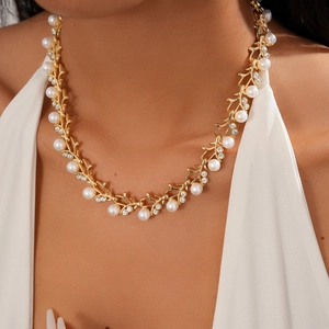 Detail of vintage golden twig necklace with white pearls and sparkling rhinestones