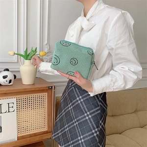 Pale green corduroy makeup bag with embroidered smiles and top zipper for daily storage