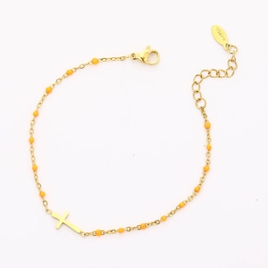 Detailed view of gold stainless steel bracelet with orange beads and cross pendant