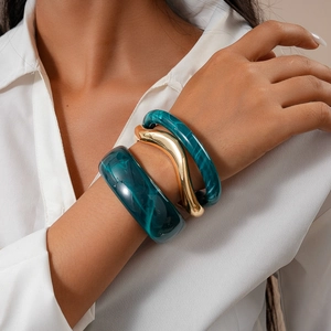 Three-piece set featuring turquoise marble resin and wavy gold metal bracelets on wrist