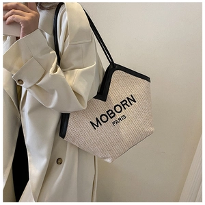 Detail of woven straw shoulder bag with black trim and MOBORN PARIS branding