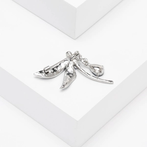 Detailed macro view of silver leaf brooch featuring a teardrop crystal pendant