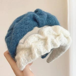 Close-up detail of soft knitted blue and cream white headbands with twisted texture