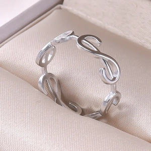 Detailed close-up of a silver link ring featuring infinity symbols on beige fabric