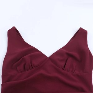 Detail of burgundy V-neck dress featuring elegant pleated bust and fine fabric texture