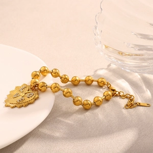 Dettaglio del bracciale a sfere dorate 18K con ciondolo a cuore leone e cristalli AMORE
