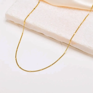 Collar de cadena dorada minimalista con detalles rectangulares en fondo de seda elegante